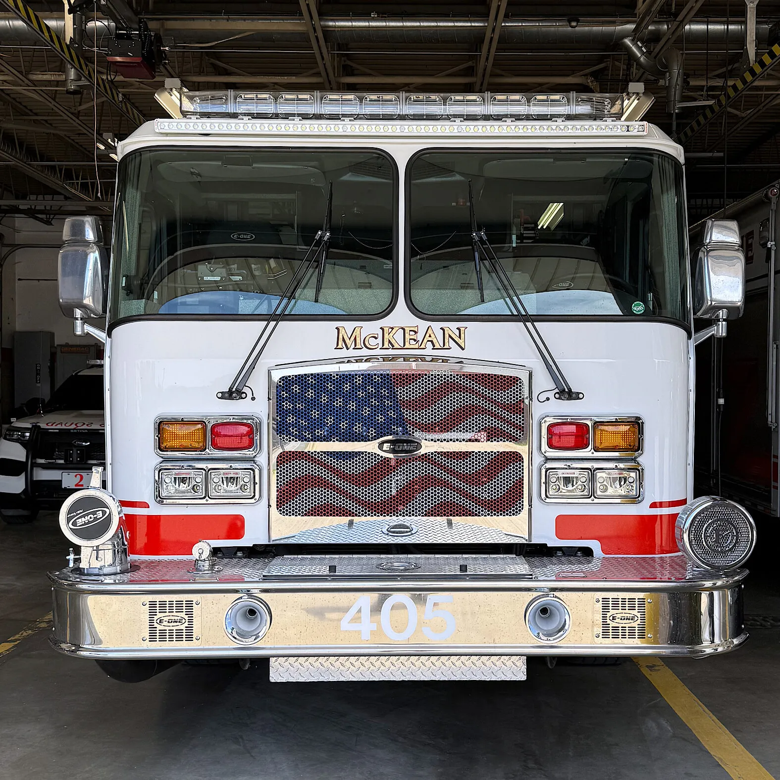 Engine 405 parked nose-out in the McKean station bay, McKean lettered in gold above a stars-and-stripes grille with 405 on the chrome front bumper