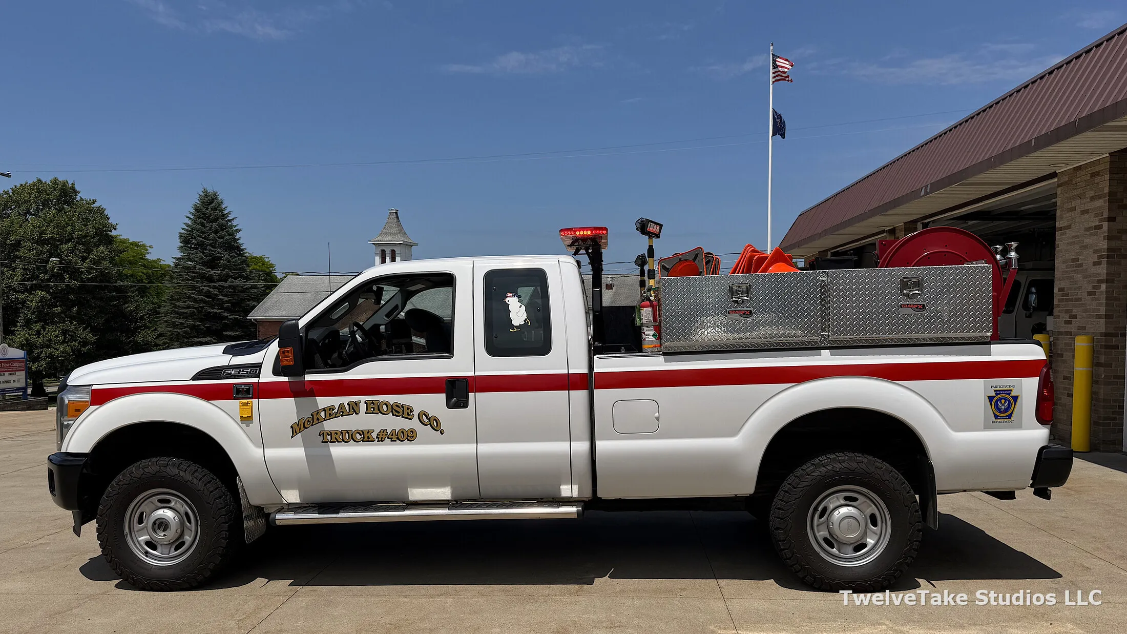 Full side view of Truck 409 showing the red body stripe, the gold TRUCK #409 door lettering and the diamond-plate toolboxes mounted across the bed.